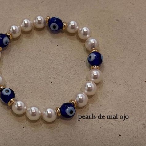 "pearls de mal ojo" this unisex bracelet is made out of blue glass evil eyes from turkey and swarovski pearls the stretchy material makes it perfect for all wrist sizes each order comes with a 12:15 jewelry bag Elegant Beaded Evil Eye Bracelet Gift, White Evil Eye Bracelet With Round Beads, White Beaded Evil Eye Bracelet, Evil Eye Pearl Bracelet, Elegant Beaded Evil Eye Bracelet, Simple Beaded Bracelets, Clay Bracelet, Unisex Bracelets, Evil Eye Bracelet