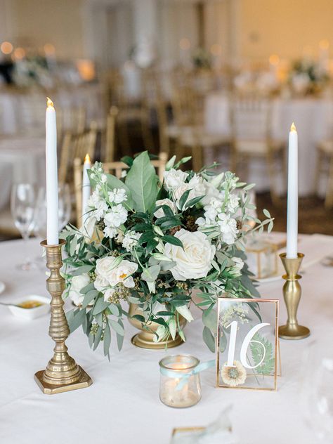 Sage Wedding Round Table Decor, Sage And White Wedding Centerpieces, Gold Candle Stick Wedding Centerpieces, Green Gold White Centerpieces, Candlestick Table Number, Wedding Table Decorations Green And Gold, Gold White And Green Floral Arrangements, Olive White And Gold Wedding, White Gold Centerpieces Wedding