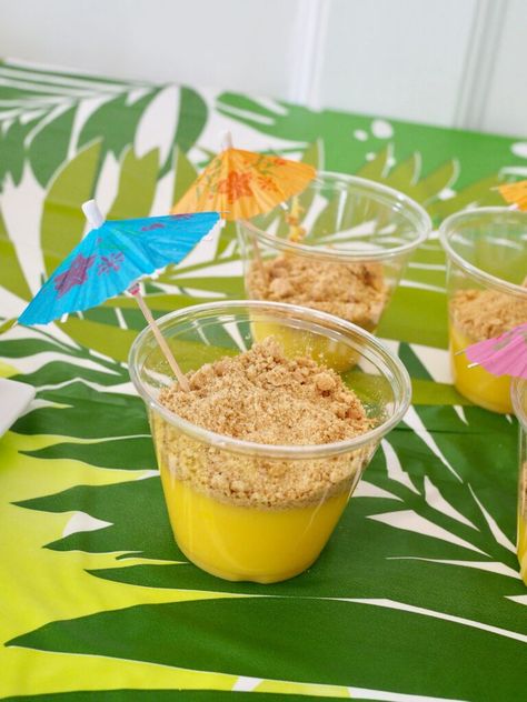 Beach Sand Pudding Cups: vanilla pudding, topped with smashed graham crackers (sand!). Then I added Hawaiian umbrellas from Oriental Trading. Preschool Luau Activities, Hawaiian Themed Activities For Kids, Aloha Activities For Kids, Hawaiian Games For Kids, Luau Snack Ideas, Hawaiian Snacks For Kids, Lava Lava Luau Vbs Crafts, Preschool Luau Party, Luau Snacks For Kids