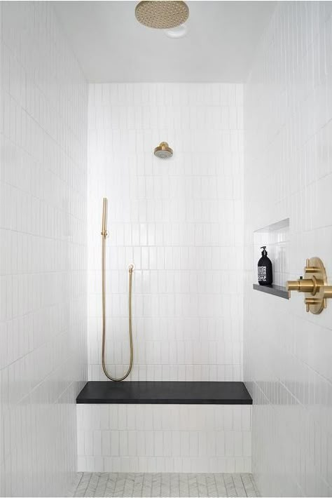 White vertical stacked shower wall tiles brings an appealing look to a walk in shower showcasing a black quartz slab shower bench a brushed gold shower kit. Mindy Gayer Design, White Tile Shower, Subway Tile Showers, Subway Tiles Bathroom, Shower Wall Tile, Gold Shower, Shower Seat, Shower Bench, Bainbridge Island