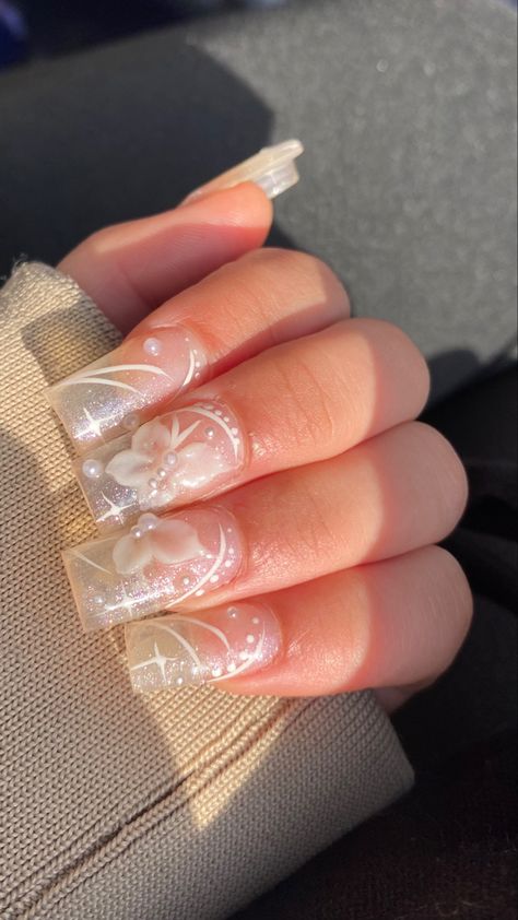 Photo of acrylics, most of the hand is covered by pulled-up beige hoodie sleeves, the fingers are bent over the sleeve to show the nails. The acrylics are translucent with very small glitter particles, drawn on the nails are stars and curved lines with dots, everything is drawn in white. The main feature of the nail are the 3D white butterflies white small faux pearls to represent the body and what looks like a thick acrylic to represent the wings, there are also small pearls in the background. 3d Acrylic Butterfly Nail Art, 3d Nail Butterfly, Clear Butterfly Nails, 3d Butterfly Nails, Butterflies Nails Acrylics, Nails Hacks, Translucent Nails, Ballerina Nails Short, Rounded Acrylic Nails