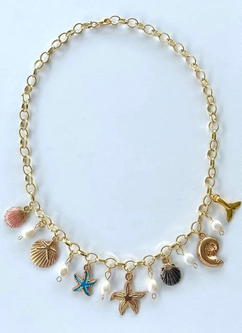 Dive into summer with our Coastal Seashell Charm Necklace! Unveil your summer glow with the perfect charm gold charm necklace. A dazzling tribute to the beauty of the ocean and the magic of sunny days.  At the heart of this enchanting piece is a radiant gold starfish, embodying the spirit of the sea and the elegance of gold. A stunning focal point that captures the sea's spirit. Surrounding it are vibrant seashells in a shimmering pink and dramatic black for a playful burst of color. Smaller colorful starfish charms add a touch of sparkle and whimsy. Luminous pearls add a chic contrast, enhancing the necklace with timeless elegance. Whether going to summer parties, casual dinners with friends, or attending special events, elevate your look effortlessly with the perfect coastal charm neckla Gold Summer Jewelry, Seashell Charm Necklace, Beach Charm Necklace, Shell Charm Necklace, Surf Jewelry, Preppy Jewelry, Pretty Jewelry Necklaces, Jewelry Accessories Ideas, Gold Charm Necklace