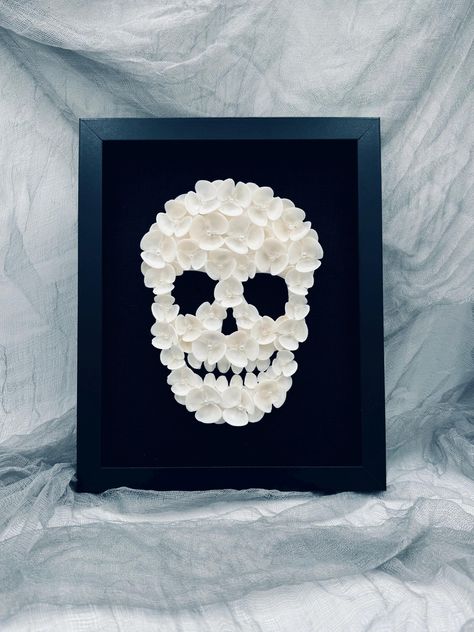 Get ready for Halloween with a unique twist on spooky decor! This one-of-a-kind seashell skeleton brings an elegant, coastal vibe to the haunting season. This skeleton is handcrafted from natural seashells creating a striking contrast against a black linen background in a black wood frame. Why You Need This: * Handcrafted Spookiness: This piece is carefully assembled by hand, ensuring that this skeleton has its own unique character and charm. * Natural Materials: Made from real seashells, this skeleton adds a touch of coastal elegance to your Halloween décor, blending the eerie with the beautiful. * Limited Edition: With only a limited number available, this exclusive skeleton is perfect for collectors and Halloween enthusiasts alike. * Perfect for Halloween: Whether you're decorating your Goth Beach, Skeleton Decor, Linen Background, Skeleton Decorations, Coastal Elegance, The Haunting, Ready For Halloween, Spooky Decor, Halloween Skull