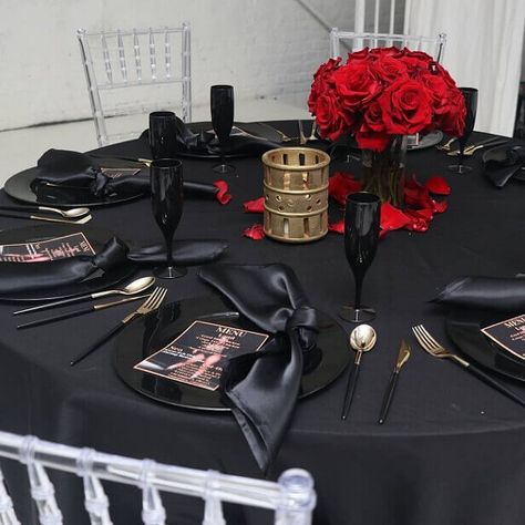 Set up a stunning black table setting and exhibit style and sophistication into your party ambiance. Dress the party table with a black polyester tablecloth and create an upscale place setting by arranging black chargers, black napkins, black handle gold cutlery, & black flutes. Spread a lovely floral charm by displaying a striking red rose flower centerpiece in the middle and scatter red rose petals all over to add a WOW factor to your tablescape. Black Tablecloth Wedding, Black Table Setting, Red Table Settings, Party Ambiance, Party Decorations Table, Masquerade Party Decorations, Gold Table Setting, Black Charger, Black Napkins