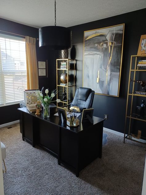 Home office painted in black, decorated with gold shelves, and gold accents. Black And Gold Home Office Ideas, Gold White Black Office, Male Desk Decor Office Ideas, Black Decor Office, His Office Decor, Grey Black Gold Dining Room, Boujee Home Office, Black And White Office Decor Ideas, Masculine Glam Office