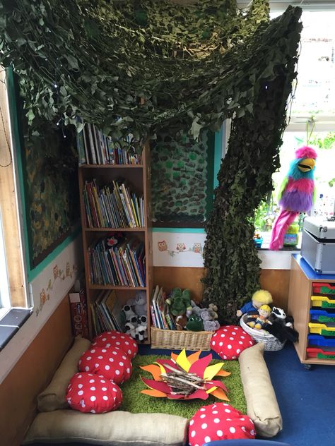 Woodland reading area  We used the bookshelf as the trunk and hung cargo netting to create the leaves.  We bought a cheap £5 BBQ and used the base for the campfire, I stuck flames shapes to the bottom and added twigs. We bought hessian fabric and created logs and toadstools. Got the rug from Amazon for £10! Children love it! Mushroom Reading Nook, Ambient Lighting Classroom, Woodland Reading Nook, Fantasy Classroom Decor, Forest Themed Reading Corner, Woodland Reading Corner, Forest Reading Corner, Garden Theme Reading Corner, Book Area Ideas