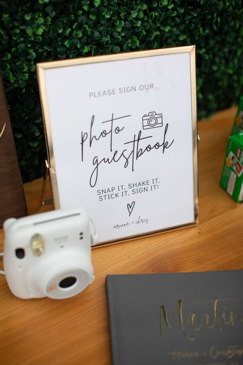 Polaroid camera wedding photo guestbook including welcome sign signage gold frame polaroid camera and hedge wall wood table Polaroid Camera Wedding Sign, Polaroid Camera Sign Wedding, Polaroid For Wedding, Polaroid Camera Table Wedding, Polaroid Pictures Wedding Display, Polaroid Wall For Wedding, Polaroid Picture Wedding Ideas, Polaroid Camera For Wedding, Wedding Camera Ideas