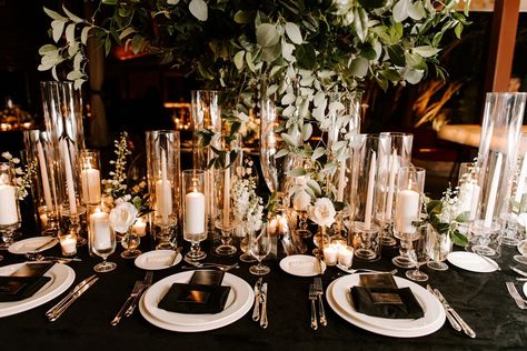 Reception tables were covered with black linens and decorated with high and low arrangements of white flowers with ample greenery, illuminated with candlelight… White And Gold Wedding Table, Wedding Table Black, Black Wedding Reception Decor, Black Table Linens Wedding, Poolside Wedding Ceremony, Black Tablecloth Wedding, Black Wedding Table Setting, Black Wedding Reception, Black White And Gold Wedding