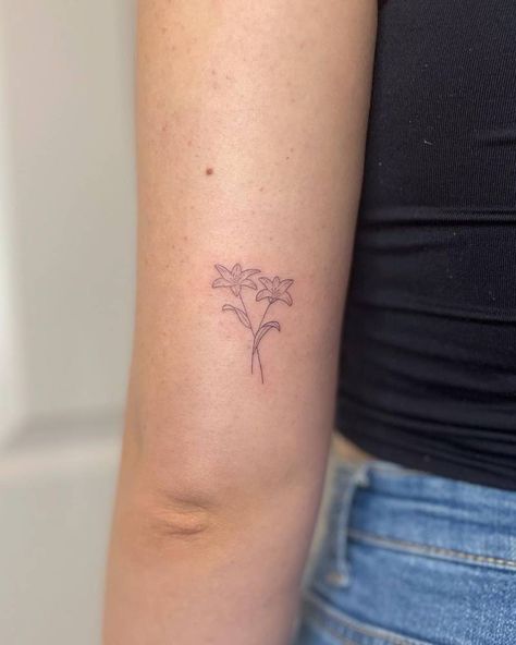 FIne line lilies tattooed on the tricep, minimalistic Minimalist Tattoo Lily Flower, Tiny Lilly Tattoo, Closed Lily Tattoo, Small Lilies Tattoo, Minimalistic Lily Tattoo, Mountain Lily Tattoo, If He Dresses The Lillies Tattoo, Mini Lily Tattoo, Lilly Finger Tattoo