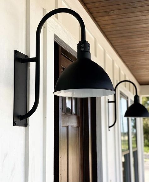 Expertly balancing its functional obligations with decorative aesthetics, the Wilcox offers multiple directional lighting alongside classic styles. For traces of uplighting, vents are cut into the neck of a classic deep bowl shade. By evoking traditional designs, this wall light feels at home in farmhouse, industrial, and contemporary décors. Farmhouse Porch Light Fixtures, Black Outdoor Farmhouse Lights, Gooseneck Porch Light, Gooseneck Lighting Outdoor Garage Doors, Gooseneck Front Porch Lights, Barn Light Front Door, Garage Door Lights Exterior Farmhouse, Barndominium Porch Lights, Black Farmhouse Exterior Lights