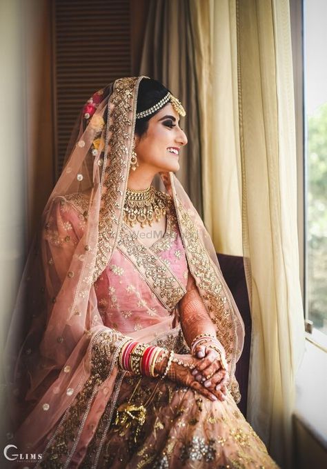 Photo of A bride in an onion pink and gold lehenga on her wedding day Onion Pink Lehenga Bridal, Pink And Gold Lehenga, Onion Pink, Bridesmaid Photoshoot, Gold Lehenga, Bridal Poses, Indian Wedding Planning, Bride Portrait, Indian Bridal Wear