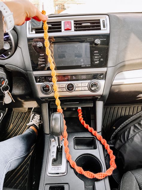 A bright-colored macrame phone charger plugged into the USB port inside a car. Color of phone charger is called sunburst which is an ombré style of red fading to yellow Boho Car Ideas, Diy For Car Decor, Cute Car Inside Decor, Artsy Car Interior, Car Decorations Crochet, Cozy Car Interior Ideas, Car Decorations Interior Boho, Boho Car Aesthetic, Car Accessories Boho