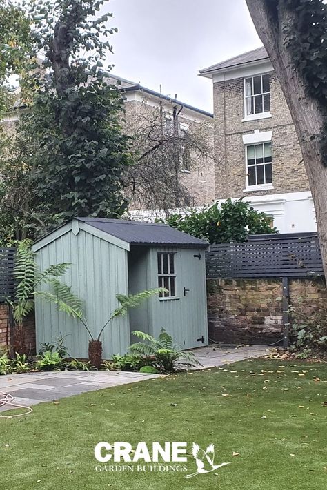 Traditional style garden shed with vertical sawn board cladding, black Onduline roof and black cast iron door furniture. The shed has  a log store included to the right of the building Black Shed With White Trim, White And Black Garden Shed, Black Sheds Gardens, Dark Green Garden Shed, Garden Shed Black, Black Shed, Farmhouse Sheds, London Garden, Traditional Garden