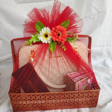 A metal basket with handbag, wrapped with red net cloth. Handbag Gift Packing Ideas, Gift Wrapping With Net Cloth, Gift Hamper Wrapping Ideas, Handbag Gift Wrapping Ideas, Hamper Decoration Ideas Gift, Hamper Wrapping Ideas, Clothes Hamper Ideas, Rakhi Hampers, Hamper Diy