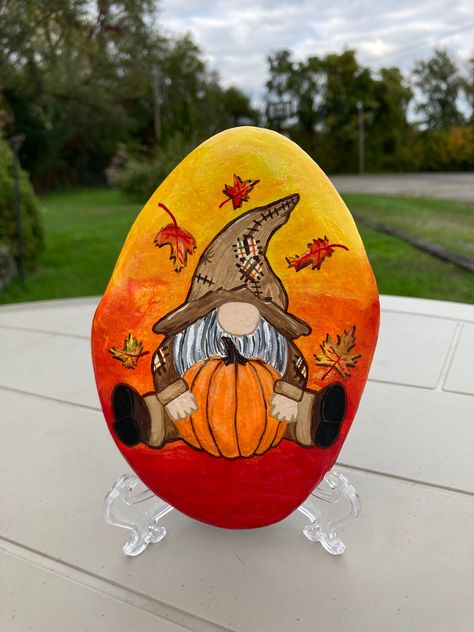 Fall Gnome Painted Rock These fall gnomes are perfect for decorating your home & garden! They make the perfect gift and add the perfect amount of fall! Each rock is hand picked from various lakes and rivers in PA. They are sealed in a gloss varnish to help protect the from weather conditions.  *No 2 rocks will be exact shape and size* Mm Painted Rocks, Rock Painting Gnomes, Fall Painted Rocks Ideas, Gnome Rock Painting, Fall Gnomes Painting, Painted Rocks For Fall, Gnome Painting Ideas, Thanksgiving Stone Painting, Fall Rock Painting