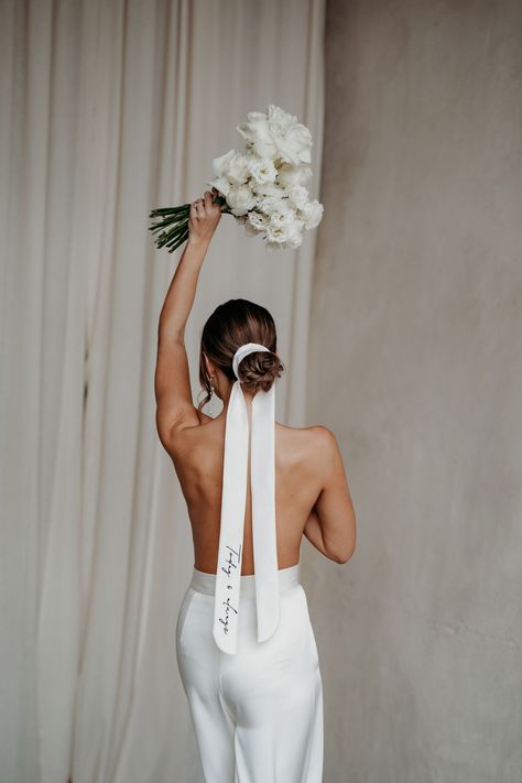 Bride with her back to teh camera wearing only a pair of bridal trousers and holding a bouquet above her head, also wears her hair tied back in a bun and secured with a long silk ribbon that has personalised embroidery on it. Wedding veil design by Rebecca Anne Designs. Bridal Hair Ribbon, Wedding Veil Styles, Veil Styles, Bride Veil, Duchess Satin, Hair Ribbon, Bride Accessories, Embroidered Wedding, Wedding Ribbon