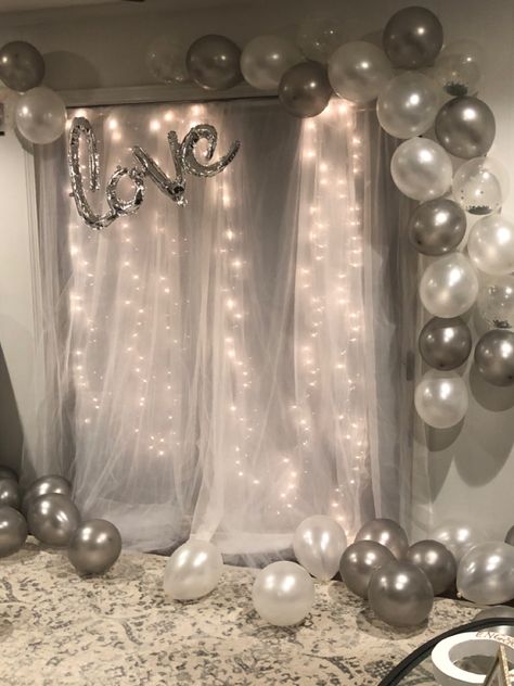 Tulle backdrop with lights + gray, gray confetti, and pearl white balloons Simple Decorations For Anniversary, Pearl White Party Decorations, Birthday Decorations With Lights, White And Silver Photo Backdrop, White Themed Birthday Party Decorations, White And Shimmer Party, White Balloon Decorations Birthday, Backdrop With Lights And Balloons, Tulle Backdrop With Balloons