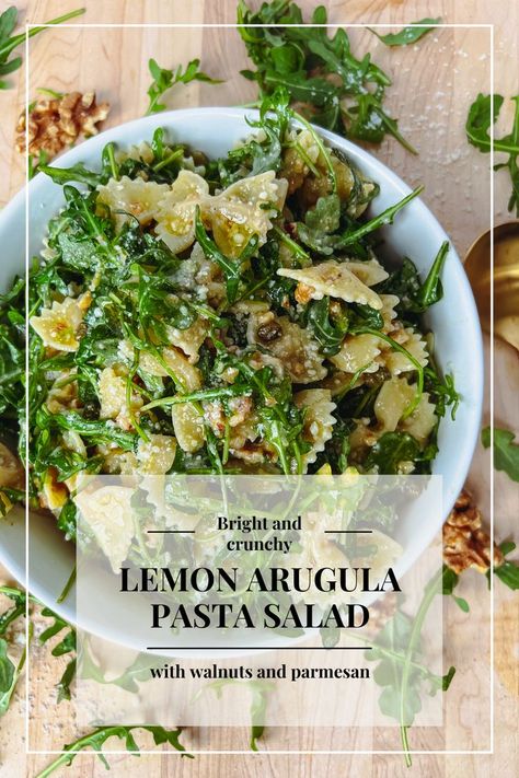 Background image shows lemon, arugula, and bowtie pasta salad in a white round bowl surrounded by walnuts and arugula, atop a light brown cutting board. Text overlay reads "Bright and crunchy lemon arugula pasta salad with walnuts and parmesan" Lemon Arugula Pasta, Arugula Pasta Salad, Parmesan Pasta Salad, Lemon Dijon Dressing, Lemon Pasta Salads, Lemon Parmesan Pasta, Bind It All, Salad With Walnuts, Gluten Free Pasta Salad