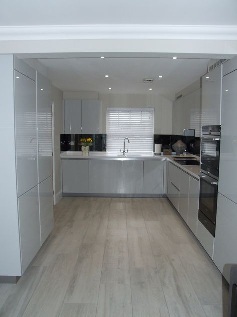 A beautifully bright and modern handleless kitchen in high gloss light grey with designer white Corian worktops. This seamless look is paired with the latest Siemens appliances and a contemporary grey mirrored glass splashback. #Bright #Modern #Whitekitchen #LightGreyKitchen #Corian #DesignerWhite #Siemens #MirroredGlassSplashback #ColliersKitchens #Contemporary #Seamless Worktop Ideas, Grey Kitchen Interior, Grey Gloss Kitchen, Light Grey Kitchen, Gloss Kitchen Cabinets, Light Grey Kitchen Cabinets, Modern Grey Kitchen, White Gloss Kitchen, Light Grey Kitchens