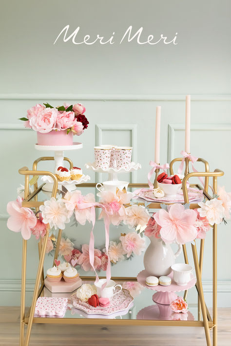 Gold bar cart styled with a floral garland and pink and red floral tableware, including cups, plates and napkins, with pastel macarons and cupcakes also on display. Laduree Table Setting, Parisian Themed Birthday Party, Laduree Party, Laduree Birthday Party, Laduree Inspired Party, Marie Antoinette Dessert Table, Doll Tea Party, Candy Boutique, Parisian Party