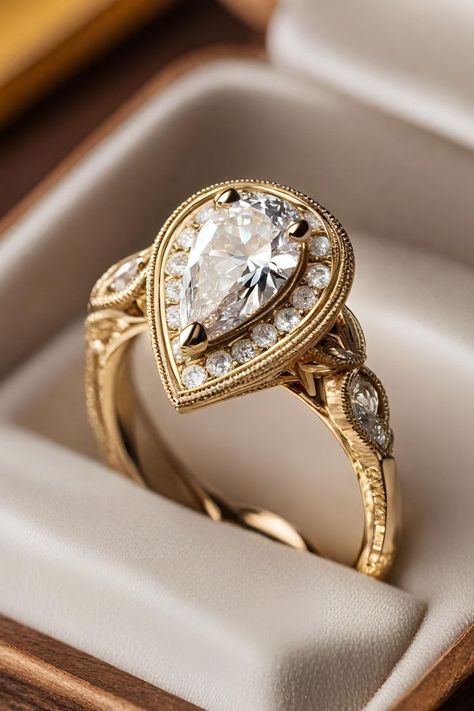 Delve into the charm of yesteryear with the Unique Vintage Halo Pear Diamond Engagement Ring, set in warm yellow gold and adorned with intricate milgrain detailing. This exquisite ring combines a pear-shaped diamond with a halo of smaller diamonds, exuding an air of sophistication and vintage elegance. Click to learn more about this stunning piece, prominently featured as number two in our list of 27 best pear engagement rings, and see how it captures the essence of antique glamour. Pear Shaped Vintage Rings, Art Deco Halo Engagement Ring, Unique Ring Designs Vintage, Vintage Rings Engagement Antiques, Vintage Gold Engagement Rings Antiques, Unique Pear Engagement Ring, Vintage Pear Engagement Ring, Gold Pear Engagement Ring, Pear Engagement Rings