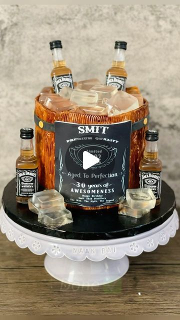 Ankita Dutta | CAKE ARTIST on Instagram: "Whiskey Barrel Cake!! 🥃 (made this one in Feb 2022 😊) With this whiskey barrel cake, many elements come together to create a very effective design. I’m quite pleased with it! 🥃🎂 It’s the little details that make a difference, such as the jelly ice cubes, the wood-textured fondant, and the fondant hoops and rivets. (The ice cubes can be made with gelatin or with agar agar, for a vegetarian option.) You can use a spray if you have access to one. Wait for the paint to dry before applying other fondant decorations. The label is edible too ☺️ Flavor - eggless chocolate with eggless chocolate buttercream (The song is so apt for this reel 🥴) #barrelcake #whiskeycake #birthdaycakeideas #fondantcake #fondantcakes #cakeformen #cakeideas #cakereels #c Edible Ice Cubes For Cakes, Whiskey Barrel Cake Ideas, Jameson Cake Ideas, Barrel Cake Design, Whiskey Cake Design, Whiskey Barrel Cake, Ice Cube Cake, Fake Ice Cubes, Barrel Cake