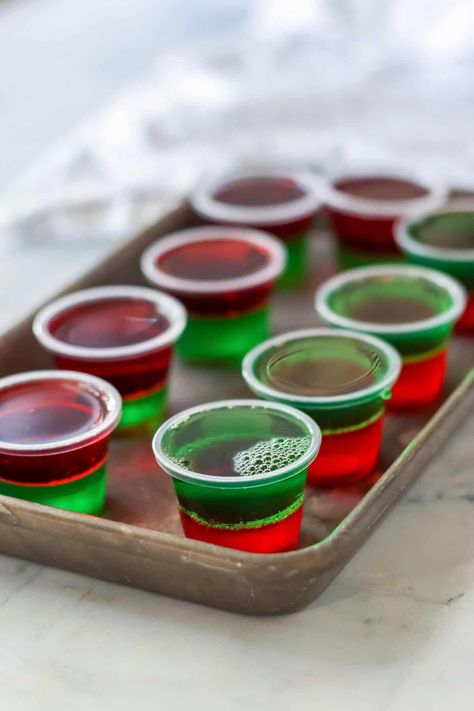 Christmas jello shots are the perfect boozy treat for the holiday season! Made with layers of red and green jello and topped with whipped cream and sprinkles, these festive jello shots are easy to make with just a few simple ingredients and perfect for holiday parties. Holiday Jello Shots, Christmas Jello Shots, Jell O Shots, Christmas Shots, Jelly Shots, Pudding Shots, Jello Shot Recipes, Grinch Party, Dessert Party