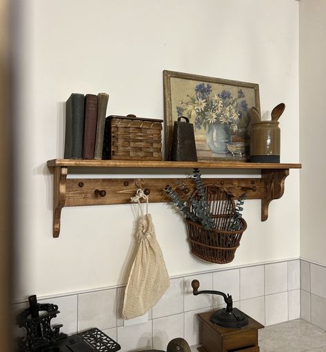 "Add character and functionality to your space with this handcrafted, pine wood peg shelf. Wooden peg shelf with hand crafted corbel ends. Pictured in Early American 36\", this is a versatile shelf that provides both character and functionality to your space. The accent ends on our shelves are hand crafted and not something that can be purchased in a big box store. Each piece is built and painted by hand in our shop. Variations in wood grain make each piece slightly different which adds to that Wood Peg Shelf, Wooden Hook Rack, Shelf With Hooks Decor, Wooden Kitchen Towel Rack, Hanging Shelf Styling, Brass And Wood Decor, Wood Shelf With Pegs, Dark Wood Wall Shelves, Cozy Cabin Home Decor