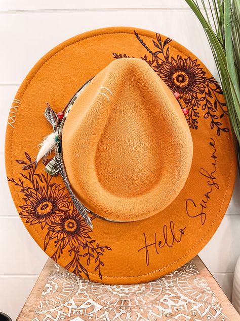 Hello Sunshine Floral Burned Hat, Floral Engraved Cowboy Hat, Sunflower Hat, Sunflower Burned Fedora, Engraved Fedora, Engraved Felt Hat, Boho Hat Elevate your style with our beautifully engraved floral hats! If you want certain colors for the feather/flower detail, please leave a note at checkout. Bands and florals/feathers may shift or fall off during shipping. The hat has an elastic band on the inside to fit many sizes. One size fits most adult heads. Hand Burned Hats, Wood Burned Hats, Pyrography Hats, Felt Hat Burning Designs, Diy Leather Hat, Burning Hats, Burnt Hat, Womens Western Hats, Cowboy Hat Design