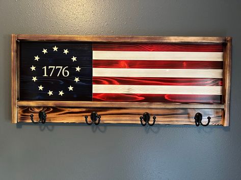 "Look no further If you're looking for that perfect rustic patriotic centerpiece, or great gift idea. This one of a kind pictured handcrafted rustic wood flag measures 39\" Wide  X 16\" tall.  WE CAN CREATE THIS COAT/HAT RACK IN ANY FLAG STYLE YOU WOULD LIKE  Each piece of wood is hand selected and uniquely prepared to ensure a truly wonderful and striking piece. The stripes are stained Red and the union is blue. The seven stripes are glued together with interior/exterior glue. Each star is meticulously engraved. The flag is then charred to perfection. The frame of the flag is made from 5/4\" Cedar, with four hooks attached.Two heavy duty aligator clips supplied for hanging.  Each flag is finished with four coats of indoor/outdoor clear Gloss or Satin Minwax Helmsman spar urethane. Flag Co Flag American Art, American Flag Coat Rack, American Flag Decor Diy, Patriotic Wood Projects, Wood Flag Ideas, Wood Craft Show Ideas, Wood Projects That Sell Ideas, American Flag Wood Projects, Patriotic Wood Crafts