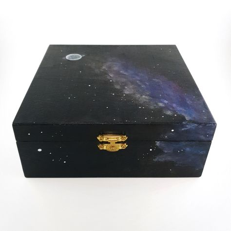 Embark on a journey through the cosmos with this hand-painted wooden box. Its black canvas is adorned with a ringed planet, stars, and nebulae, capturing the beauty and mystery of the universe. 🌌 Whether you use it to store trinkets or simply as a decorative gem, it's a reminder of the vastness and wonder of space. Explore the stars from the comfort of your space. #GalaxyBox #SpaceInspired #SpaceArt #Handpainted #EtsyFinds #WeAreMadeOfStarstuff Black Box Painting Ideas, Wooden Box Painting Ideas Boyfriend, Memory Box Ideas Diy Paint, Galaxy Box Painting, Painting Small Wooden Boxes, Witch Boxes Painted, Small Jewelry Box Painting Ideas, Ringed Planet, Upcycle Jewelry Box