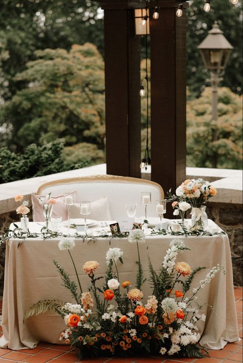 The sweetheart table with Italian ruscus runner, bud vases and a ground arrangement in front. This peach and orange palette was perfect for a summer garden wedding. Sweetheart Floral Arrangement, Front Table Decor Wedding, Spring Sweetheart Table Wedding, Sweetheart Table Ground Flowers, Wedding Floral Centrepiece, Summer Wedding Sweetheart Table, Wild Flower Sweetheart Table, Wedding Decor Sweetheart Table, Sweetheart Table With Bud Vases