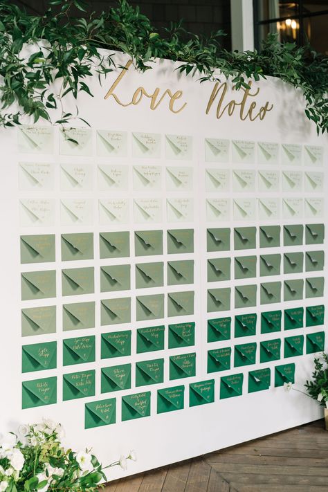 A green seating chart for wedding reception with greenery and flowers surrounding it. Perfect for a wedding that has green in their color palette. The couple wrote a note to each guest. Wedding Seating Assignment Display, Creative Table Seating Chart Wedding, Matches Seating Chart, Emerald Seating Chart, Big Wedding Seating Chart, Wedding Favors Seating Chart, Reception Seating Chart Layout, Thank You Note Seating Chart, Wedding Table Assignment Ideas Reception Seating