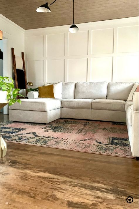 Living room with colorful rug, light gray couch, white walls, board and batten, modern lighting Batten Board Living Room, Behind The Couch Accent Wall, Light Gray Board And Batten Wall, White Board And Batten Living Room, Large Board And Batten Wall Living Room, Wainscoting Behind Couch, Grey Couch Accent Wall, Accent Wall With Gray Couch, Accent Walls Behind Couch