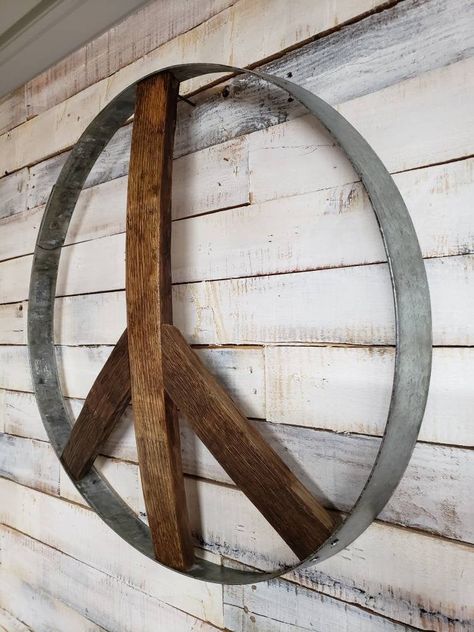 "Peace sign made from authentic wine barrel ring and stave(wood). Each order may differ in size and color since not all barrels are the same. Wood is secured to metal ring and support brackets are placed behind each joint in the sign. The rings are 24\" in diameter. All finished products are sealed with varnish unless specified by the customer. These are very sturdy and will give a great conversational piece to your space. PLEASE NOTE THAT FREE SHIPPING ONLY APPLIES TO WITHIN THE CONTINENTAL U.S Metal Peace Sign, Wood Peace Sign, Metal Wire Sculpture, Diy Whiskey, Barrel Crafts, Wine Barrel Art, Eclectic Garden, Barrel Art, Wine Barrel Crafts