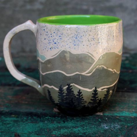 This mag is made by pottery wheel, then hand illustrated, this mountain made in graffiti technique, and forest and sky hand painted. More in our shop https://www.etsy.com/shop/LebidCeramics Mountain Bowl Pottery, Pottery Mug Mountains, Ceramic Mug Mountains, Tree Pottery Painting, Mug Painting Ideas Mountains, Hand Painted Mugs For Men, Pottery Painting Ideas Mountains, Pottery Painting Ideas Guys, Mountain Pottery Painting Ideas