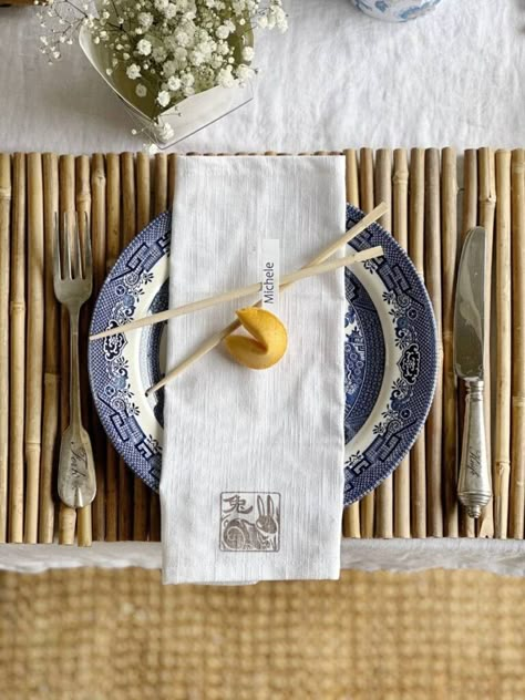 It's tablescape day for my dinner club and we're hosting an Asian inspired gathering. I'm sharing the best ideas for hosting a Chinese themed dinner party. My great grandmothers blue transferware with an Asian pattern was the inspiration for my Chinese themed table decor. Bamboo placemats, chopsticks, fortune cookies and Chinese takeout containers were other elements I incorporated. An Asian pattern teapot and the take-out containers made great vases for flowers for the centerpiece. Asian Table Setting Dinner Parties, Chinese Table Setting Ideas, Hibachi Party Table Setting, Japanese Inspired Tablescape, Asian Inspired Tablescape, Chinese Takeout Party, Chinese Food Dinner Party, Asian Dinner Table Setting, Chinese Dinner Party Decorations