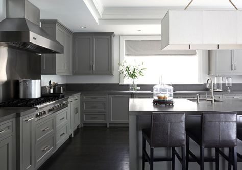 Gray kitchen with gray shaker cabinets paired with dark gray countertops framing stainless steel hood with stainless steel cooktop backsplash over integrated stove situated above pot and pan drawers. Blue Gray Kitchen Cabinets, Black And Grey Kitchen, Light Grey Kitchen Cabinets, Grey Kitchen Floor, Light Grey Kitchens, Light Gray Cabinets, Grey Kitchen Designs, Dark Grey Kitchen, Grey Wood Floors