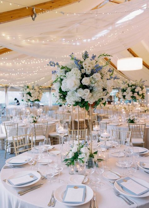 A beautiful tall arrangement made up of roses, hydrangea, delphinium and greens surrouded by candlelight and soft twinkling lights above. Hydrangea Aisle Wedding, Wedding Hydrangea Centerpiece, Elegant Classy Wedding Decor, Light Blue Gold Wedding, Light Blue And Gold Wedding, Wedding Table Lighting, Castle Hill Inn Wedding, Soft Blue Wedding, Wedding Ireland