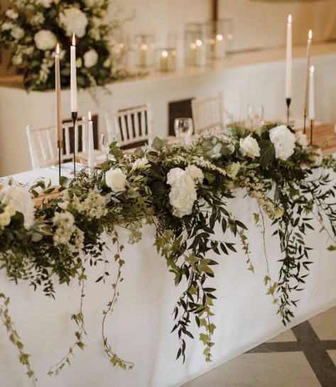 Favorite look for the couples table. Love the greens hanging down. Do not want it very big, bunchy, or voluminous White Wedding Head Table Decor, Wedding Head Table Greenery Garland, Main Table Wedding Decoration Greenery, Top Table White Flowers, Wedding Flowers Main Table, Centerpieces Wedding Farm Table, Bride And Groom Table Greenery, Wedding Flowers White And Green Centerpieces, Sweetheart Table Wedding Eucalyptus