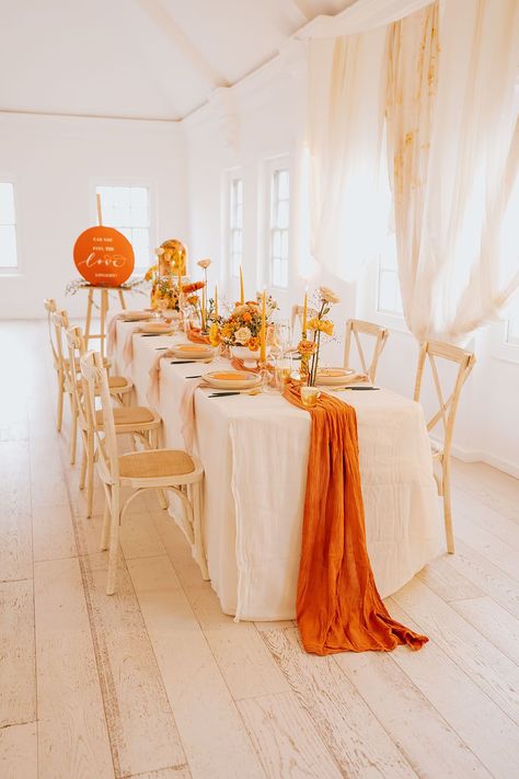 golden wedding table decor with an orange table runner, yellow taper candles and flower arrangements and gold cutlery Orange Theme Decoration, White And Orange Table Setting, Orange Theme Table Decor, Orange And Yellow Table Setting, Orange And Gold Party Decorations, Orange And Yellow Decorations, Orange Theme Table Setting, Orange White And Gold Decorations, Shades Of Orange Party Decor