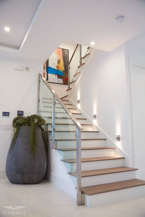 Glass railing enhances this beautiful, contemporary staircase. Slim side mount posts anchor the railing without obstructing its clear lines, while steel clips hold the glass securely in place. The result is a minimal and sleek stairway. #design #interiordesign #DIY #renovation #Viewrail #stairs #staircase #architecture #railing #glassrailing #stairway #modern #contemporary #minimalism Modern Staircase Railing, Glass Staircase Railing, Glass Railing Stairs, Vstupná Hala, Modern Stair Railing, Staircase Design Modern, Contemporary Stairs, Staircase Railing Design, Contemporary Staircase