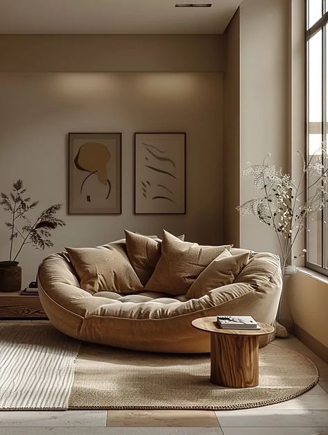 The image is a living room. There is a large, round couch in the center of the room ->> more details in ai-img-gen.com Wall Behind The Couch, Round Couch, Cozy Home Library, Behind The Couch, Small Round Table, Two Paintings, Brown Couch, Cozy Couch, Comfy Couch