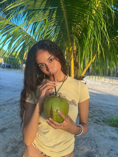 Coconut, coconut trees, island girl, island vibes, island aesthetic, coconut girl, waist beads, island outfit, wavy hair, natural makeup, relaxing vibes, aesthetic pic, tan, palm trees, sand, beachy vibes, beach, yellow tee, y2k graphic tee, drinking coconut Aesthetic Coconut Girl, Aesthetic Coconut, Island Aesthetic, Puerto Rico Vacation, Barbie Summer, Island Outfit, Coconut Trees, Beachy Vibes, Waist Beads