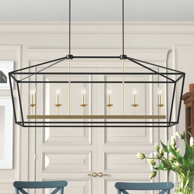 This 6-light linear pendant creates a bright focal point in your kitchen or dining room. It’s made from steel, with a lightly distressed, hand-painted black and gold finish. This pendant has an airy, geometric lantern silhouette that adds a modern touch. It hangs from two parallel downrods and a sloped ceiling-compatible canopy. Its six candle-style fixtures hold six 60W bulbs (sold separately). We love that this pendant is compatible with a dimmer switch, to let you choose the ambiance in your Black Pendant Light Dining Table, Black And Gold Chandelier Dining Room, Linear Chandelier Over Island, Linear Chandelier Dining Room, Linear Kitchen Island Lighting, Lantern Silhouette, Real Candles, Geometric Lantern, Kitchen Island Linear Pendant