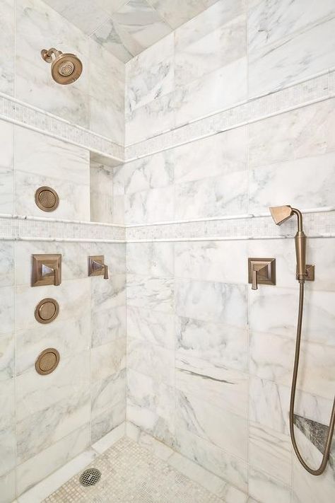 Calcutta gold marble clad walk in shower is accented with white tumbled marble mosaic border tiles and fitted with a brushed gold shower kit and sprayer fixed above mosaic marble grid floor tiles. Bathroom White Gold, White Marble Shower, Tile Shower Niche, Calcutta Gold Marble, Marble Shower Tile, Calcutta Gold, Shower Wall Tile, Bathroom White, Marble Showers