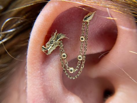 🐉✨ Embrace the power of the dragon with our custom "1976" piece from @junipurrjewelry , a 14k gold dragon connected with a chain. 🌟✨ This stunning upgrade to an existing piercing symbolizes strength, wisdom, and good fortune. Our talented piercer @faeriepokes helped customize to this client her idea and create something truly special that fits her anatomy. Make an appointment with our professional piercers to create your self your new unique piercing statement!! 🌙💎 #DragonJewelry #Custo... Junipurr Jewellery, Ear Scape, Unique Piercing, Unique Ear Piercings, Chinese Dragons, Dragon Earrings, Piercings Unique, Body Modification, Gold Dragon