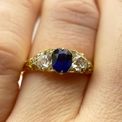 Have we just uncovered the perfect engagement ring? We are pretty convinced we have! This exquisite 3-stone ring features a central oval-cut sapphire, estimated at approximately 0.85ct, in a stunning deep blue hue. Staying on the track of some of the best diamonds in the have seen, it is flanked by two bright and eye clean old mine cut diamonds, estimated at approximately 0.38ct and 0.42ct respectively (one diamond is slightly deeper). Crafted from fine 18ct gold, the mount boasts a beauti... Saphire Engament Ring Gold Band, Color Stone Ring, The Perfect Engagement Ring, 3 Stone Rings, Sapphire Engagement Ring, Color Stone, Perfect Engagement Ring, Best Diamond, Blue Hues