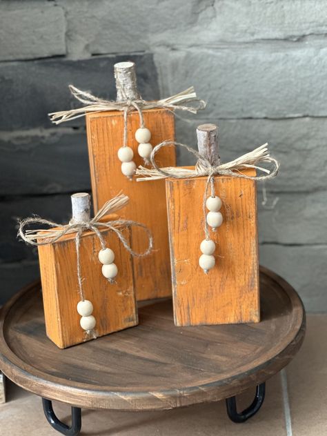 Rustic wood pumpkins (set of 3) for fall decor are charming, handcrafted decorations that bring warmth and a touch of nature into your space. These pumpkins are typically made from reclaimed or distressed wood, giving them a weathered, vintage appearance. Each pumpkin can vary in size, often carved or assembled from wooden planks to create a three-dimensional shape. The wood may be stained in various shades of brown, orange, or left in its natural, raw state to enhance the rustic feel. Some might feature knots, cracks, or imperfections in the wood, adding to their authentic, handcrafted look. These rustic wood pumpkins can be displayed individually or grouped together, perfect for mantelpieces, tabletops, or as part of a larger fall-themed vignette. Their earthy tones and natural materials Stump Pumpkins Diy, Wood Decor To Sell, Wooden Outdoor Decor, Wooden Pumpkins Painted, Scrap Wood Pumpkins, Scrap Wood Pumpkins Diy, Scrap Wood Fall Projects, Fall Blocks Wood Crafts, Wood Fall Crafts