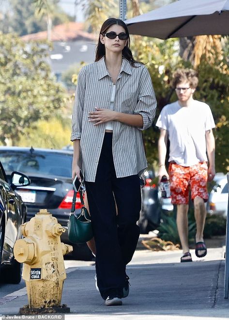 Kaia Gerber is seriously stylish in a striped button-up shirt and black pants while taking a stroll | Daily Mail Online Outfits With Striped Shirts, Button Down Outfit, Kaia Gerber Style, Black Button Up Shirt, Models Off Duty Style, Shirt Dress Outfit, October 5, Kaia Gerber, 가을 패션